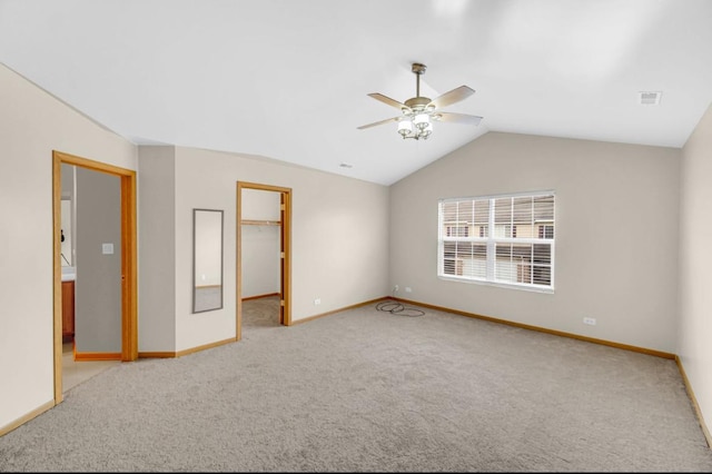 spare room featuring carpet, baseboards, vaulted ceiling, and a ceiling fan