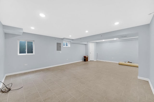 basement featuring recessed lighting, electric panel, and baseboards