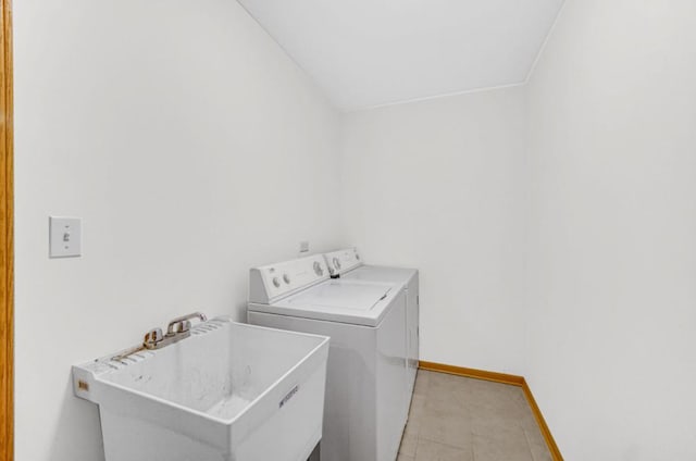 washroom with light tile patterned floors, laundry area, a sink, baseboards, and washer and clothes dryer