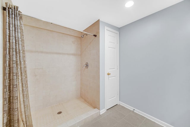 bathroom with tile patterned flooring, a tile shower, and baseboards