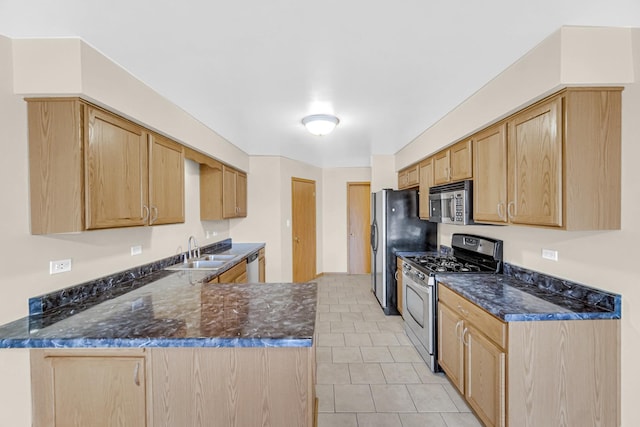 kitchen with a peninsula, appliances with stainless steel finishes, a sink, and light brown cabinetry