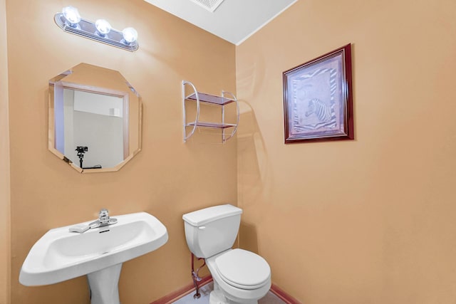 half bath featuring a sink, toilet, and baseboards