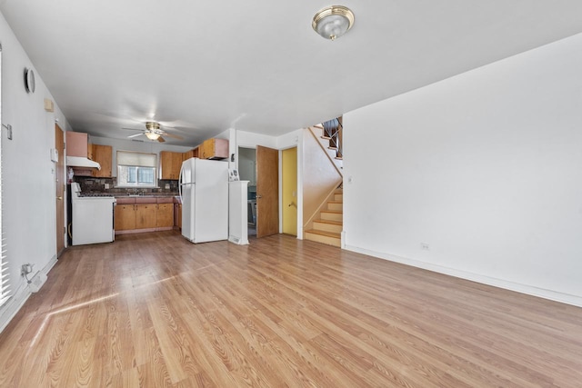 kitchen featuring white appliances, dark countertops, ceiling fan, light wood-type flooring, and under cabinet range hood