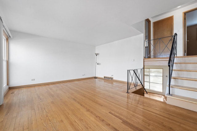 interior space featuring wood-type flooring, stairs, visible vents, and baseboards