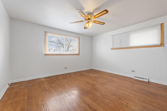 empty room with wood-type flooring, visible vents, ceiling fan, and baseboards