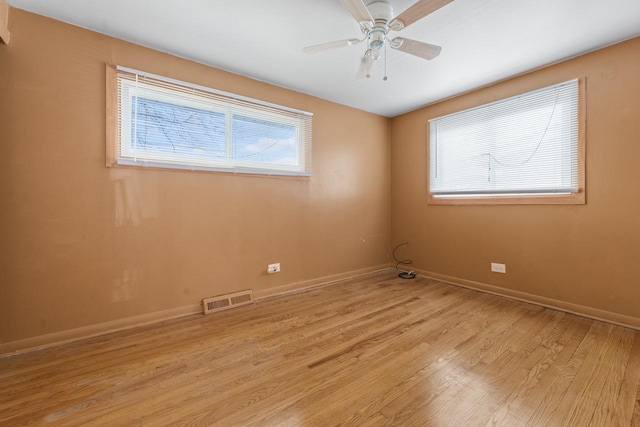 spare room featuring light wood-style floors, baseboards, visible vents, and ceiling fan