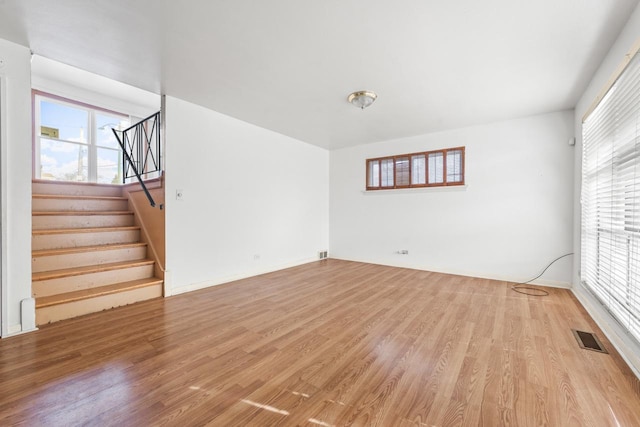 unfurnished living room with light wood-type flooring, visible vents, and stairs