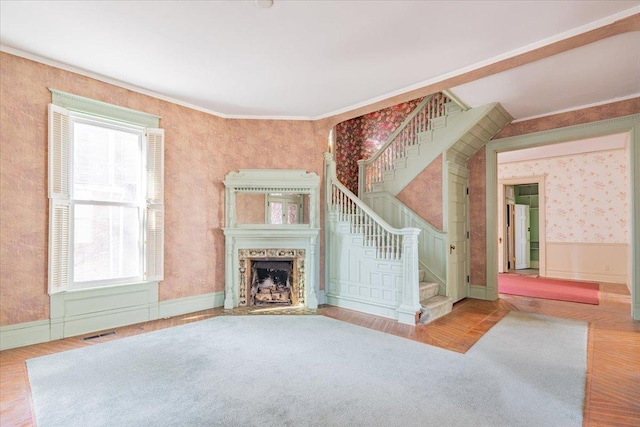 unfurnished living room with plenty of natural light, a fireplace, wood finished floors, and wallpapered walls