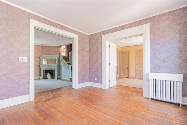 unfurnished room with radiator heating unit, a fireplace, ornamental molding, and wood finished floors