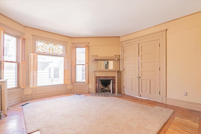 unfurnished living room with wood finished floors, a high end fireplace, and a wealth of natural light