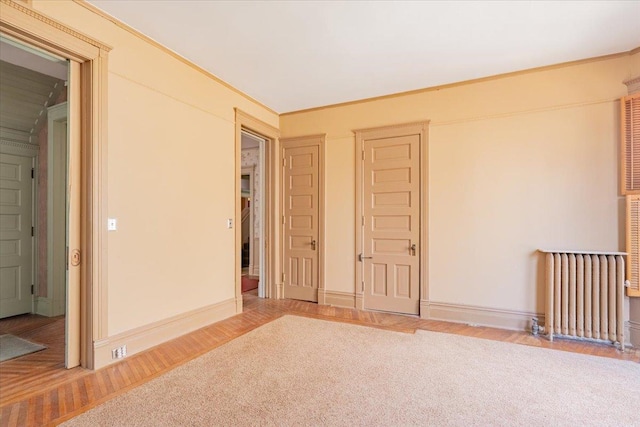 unfurnished bedroom with ornamental molding, radiator, baseboards, and wood finished floors