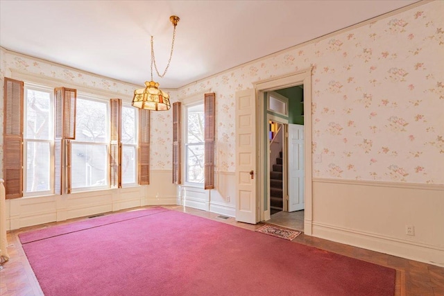 unfurnished room with wallpapered walls, visible vents, stairway, and a wainscoted wall