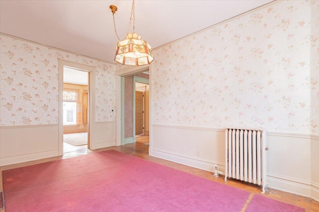 spare room featuring radiator, wainscoting, and wallpapered walls