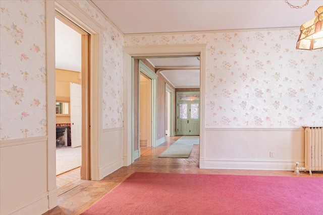 unfurnished room featuring radiator heating unit, wainscoting, carpet flooring, and wallpapered walls