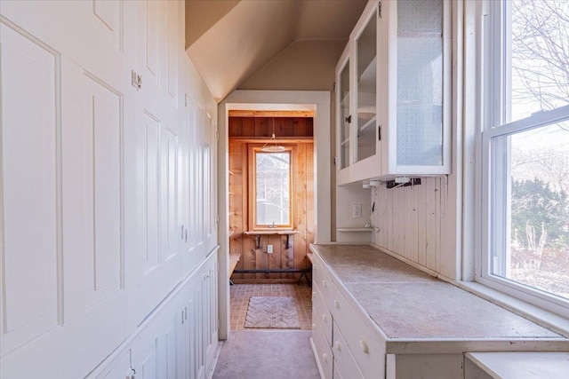 mudroom with lofted ceiling and wooden walls