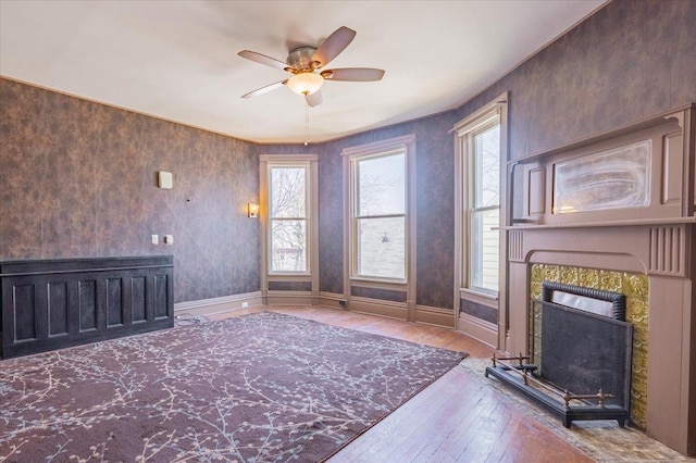 unfurnished living room with ceiling fan, baseboards, hardwood / wood-style floors, and a tile fireplace