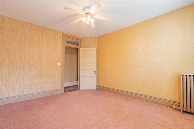 spare room with carpet floors, wallpapered walls, a ceiling fan, and radiator