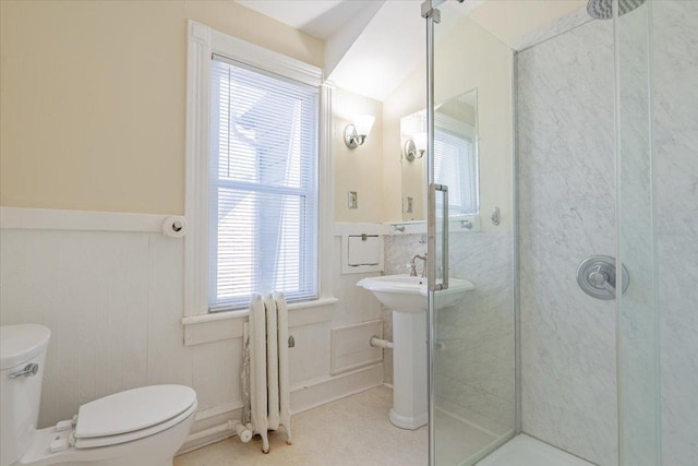 bathroom featuring toilet, a stall shower, radiator, and wainscoting