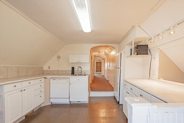 kitchen with arched walkways, dark floors, white cabinetry, a sink, and white appliances