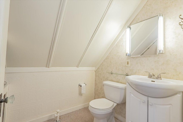 half bath featuring lofted ceiling, baseboards, vanity, and toilet