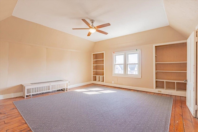 empty room featuring built in features, baseboards, lofted ceiling, wood-type flooring, and ceiling fan