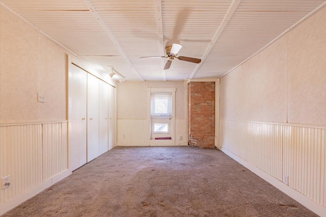 empty room featuring carpet, ceiling fan, and wainscoting