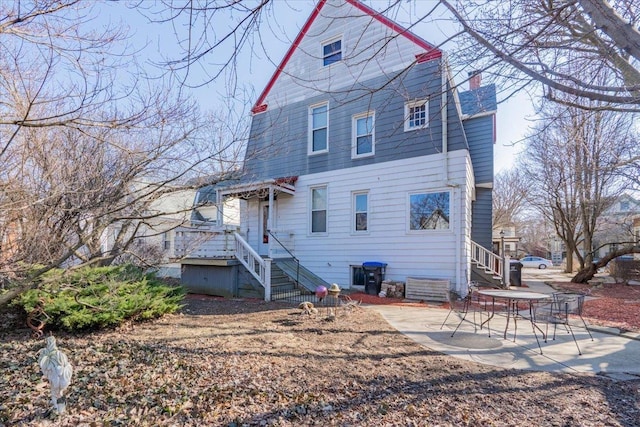 back of house with a patio and a chimney