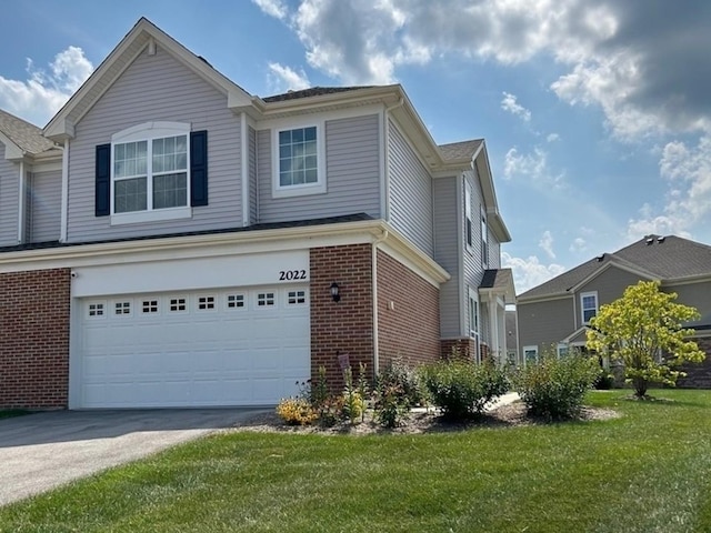 view of front of home featuring a garage, concrete driveway, brick siding, and a front yard