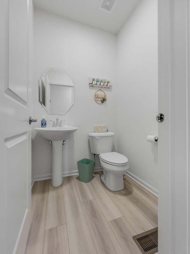 bathroom featuring toilet, wood finished floors, visible vents, and baseboards