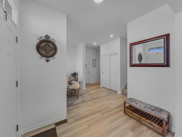 hallway featuring recessed lighting, visible vents, light wood-style floors, baseboards, and stairs