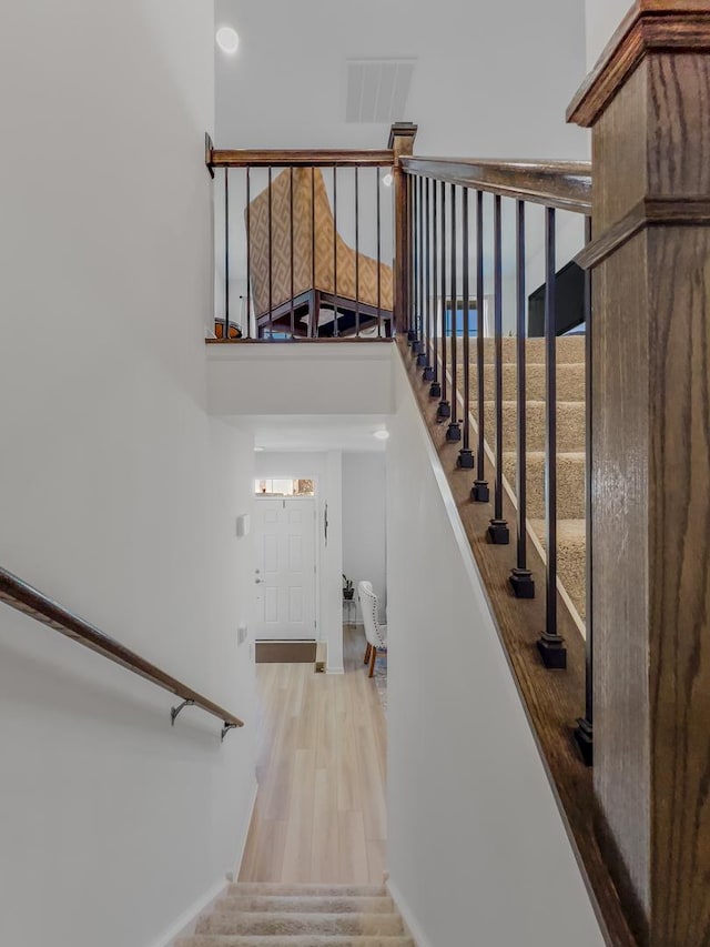 stairway featuring a towering ceiling, visible vents, and wood finished floors