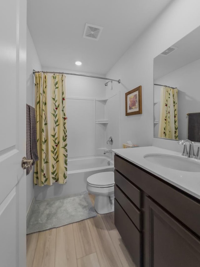 bathroom featuring visible vents, shower / bathtub combination with curtain, toilet, vanity, and wood finished floors