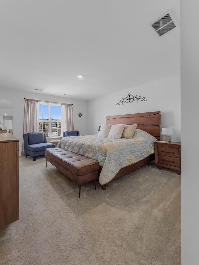 bedroom featuring light carpet, arched walkways, and visible vents