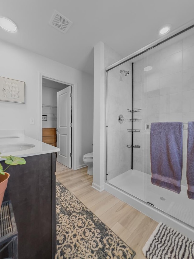 bathroom with visible vents, a shower stall, toilet, and wood finished floors