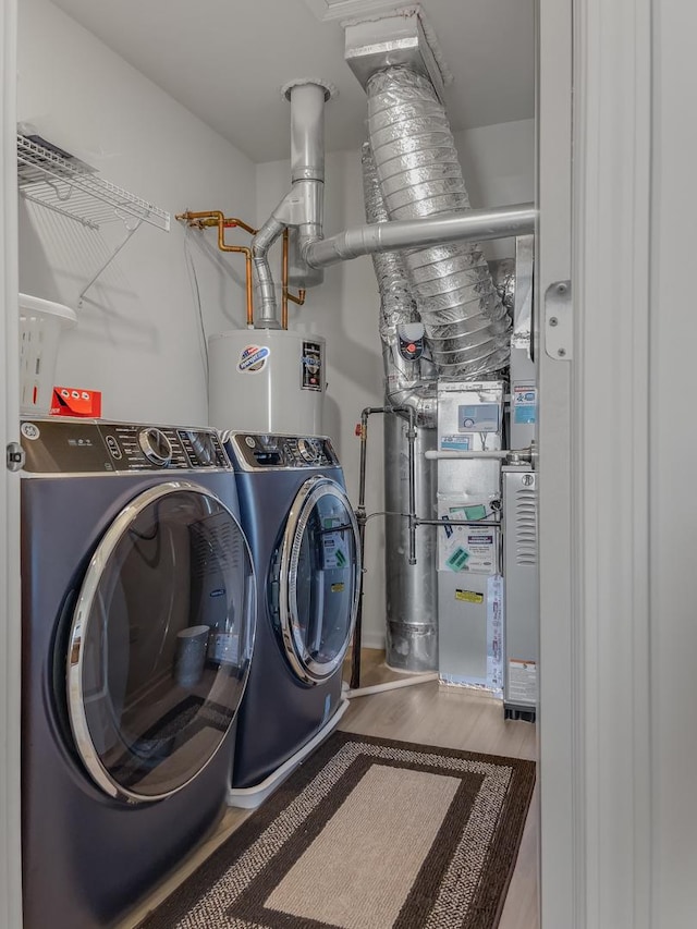 laundry room with laundry area, water heater, separate washer and dryer, and wood finished floors