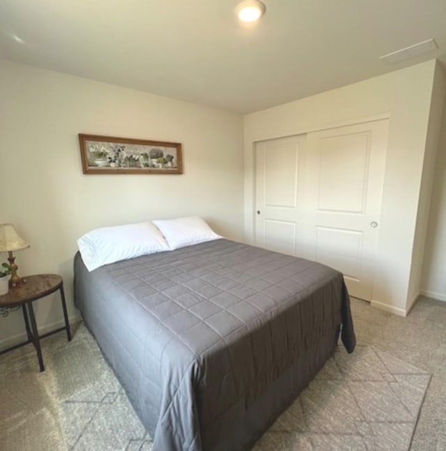 carpeted bedroom featuring a closet and baseboards