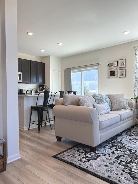 living room with light wood finished floors, baseboards, and recessed lighting