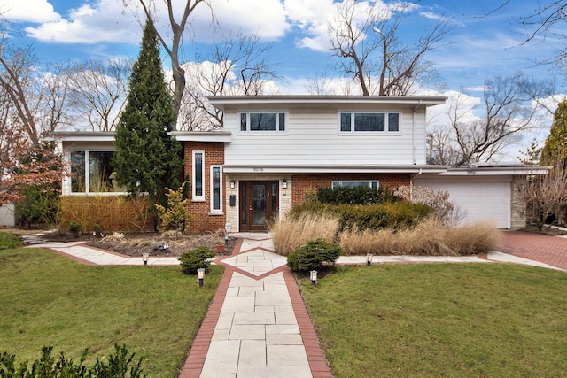 split level home with decorative driveway, brick siding, an attached garage, and a front lawn