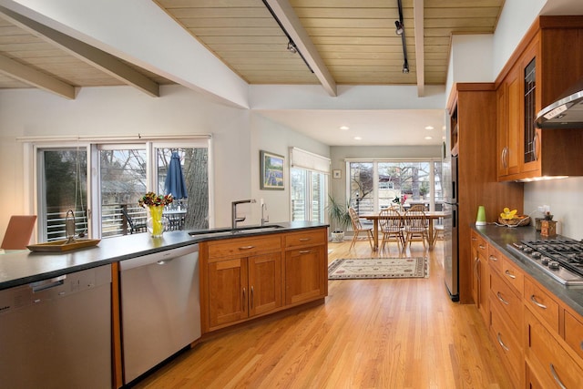 kitchen featuring dark countertops, appliances with stainless steel finishes, brown cabinetry, and a sink