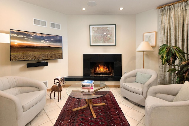 living area with visible vents, a lit fireplace, and tile patterned floors