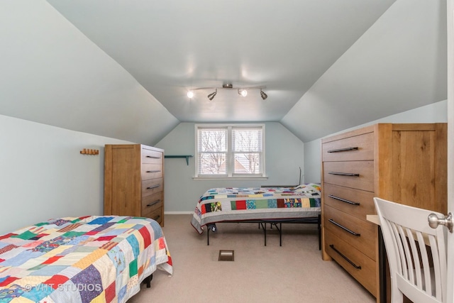 bedroom with track lighting, light colored carpet, and vaulted ceiling