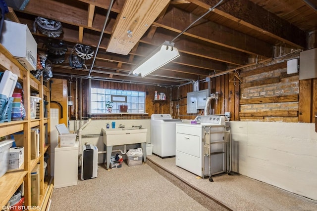 basement featuring electric panel, wood walls, and washer and clothes dryer