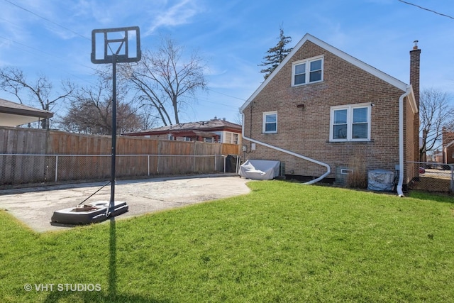 rear view of house with a patio, a lawn, a fenced backyard, and brick siding