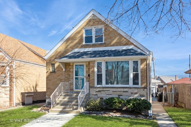 bungalow-style house featuring stone siding, brick siding, roof with shingles, and fence