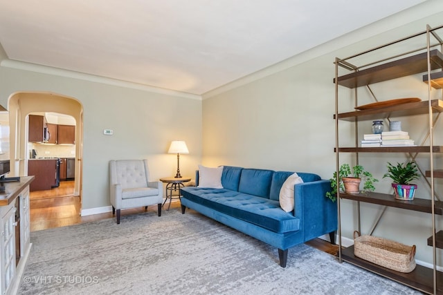 living room with baseboards, arched walkways, wood finished floors, and ornamental molding