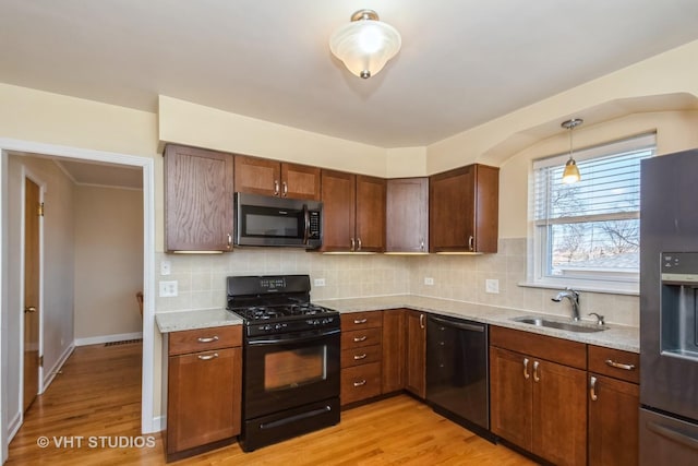 kitchen featuring a sink, stainless steel appliances, backsplash, and light wood finished floors