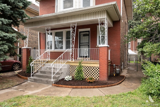 doorway to property featuring covered porch and brick siding