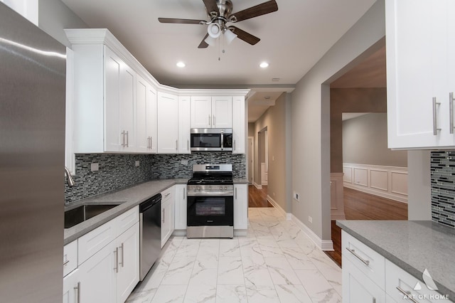 kitchen with marble finish floor, appliances with stainless steel finishes, backsplash, and a sink