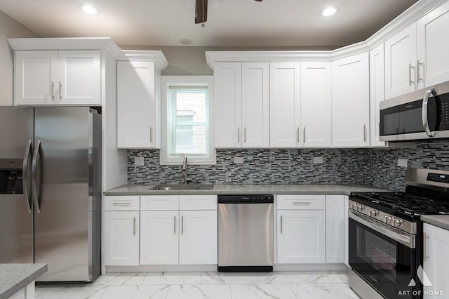 kitchen with marble finish floor, appliances with stainless steel finishes, a sink, and white cabinetry