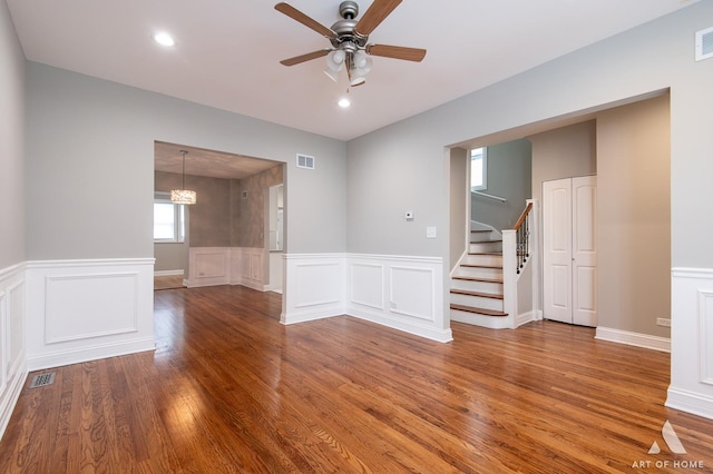 spare room featuring stairway, ceiling fan, visible vents, and wood finished floors